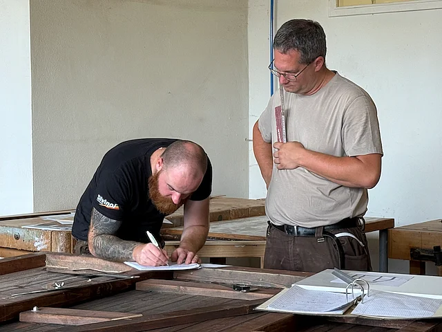 Mitarbeiter der Werkhof-Schreinerei vermessen eine Marktbude der Stadt Regensburg und dokumentieren Konstruktions- und Materialdaten für zukünftige Projekte.