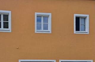 Hausfassade gestrichen mit weiß abgesetzten Fensterumrandungen