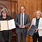 Gebrauchtwarenhausleiterin Angela Weber präsentiert die Urkunde zum Umweltpreis der Stadt Regensburg. Werkhof-Geschäftsführer Peter Astashenko hält die Auszeichnung in den Händen. Bürgermeisterin Dr. Helene Sigloch überreicht eine Flasche Salutaris-Wein aus Regensburg.