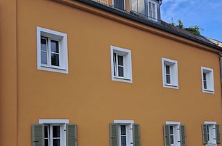 Hausfassade gestrichen mit weiß abgesetzten Fensterumrandungen