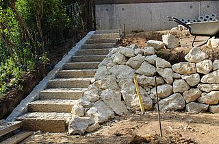 Granit Kleinsteinverlegung im Stufenbereich und Errichtung einer Trockenmauer