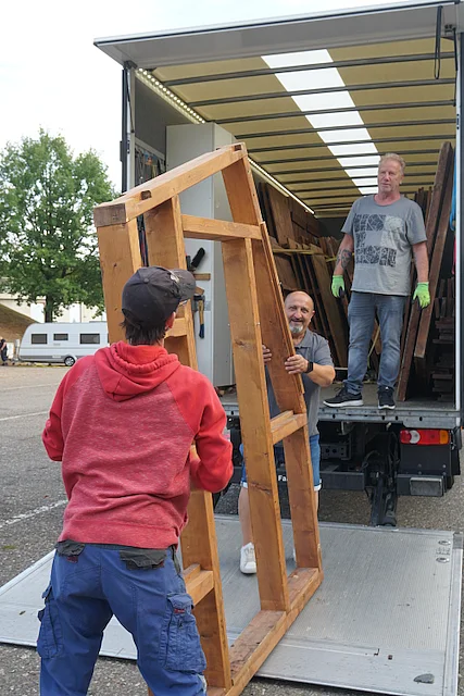 Mitarbeitende des Werkhofs laden Bauteile für Dultbuden von einem Lkw ab.