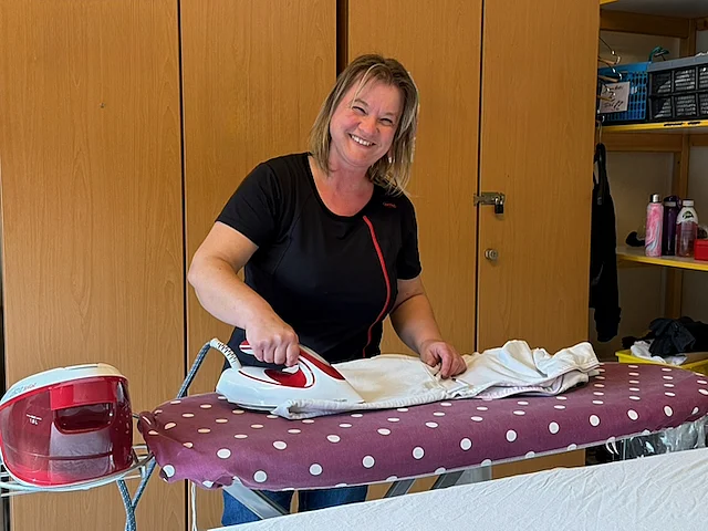 Beatrice Fröde beim Bügeln in der Wäscherei des Werkhofs Schwandorf, sie lächelt dabei freundlich in die Kamera