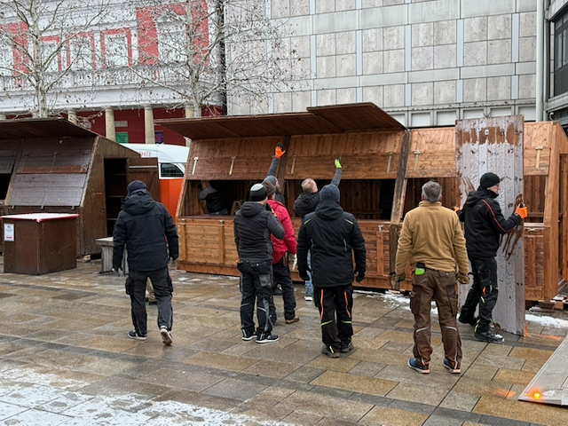 Teamarbeit beim Rückbau: Während einige Mitarbeitende des Werkhof Regensburg die Seitenteile der Buden abbauen, warten andere darauf, die Teile gemeinsam zum LKW zu transportieren.