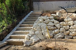 Granit Kleinsteinverlegung im Stufenbereich und Errichtung einer Trockenmauer